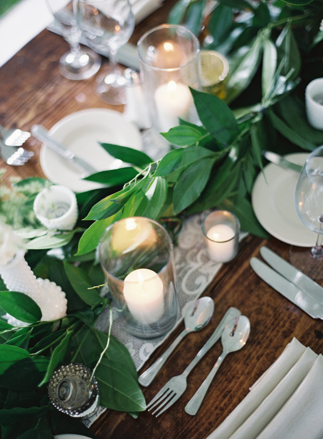 Mesas de invitados decoradas con hojas verdes y velas